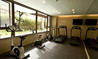 a well - equipped exercise room with various fitness equipment , such as treadmills , stationary bikes , and weight machines at Alishan House