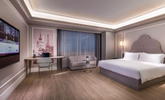 There is a large bed in the middle room of the hotel, accompanied by a table and chairs at Mercure Shanghai Hongqiao SOHO
