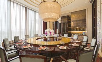 There is a large dining table and chairs in the middle room, complemented by an ornate chandelier hanging above at the International Trade City, Yiwu - Marriott Executive Apartments