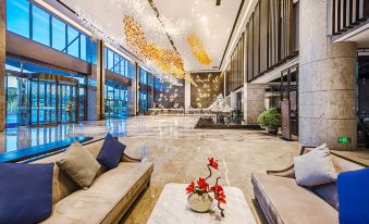 The lobby features a sleek, modern design highlighted by a prominent chandelier and glass panels at Orchid Sea Hotel