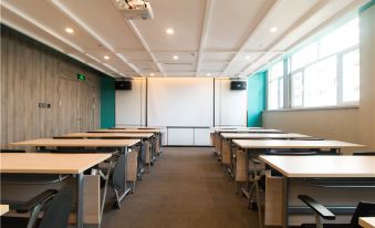 a large , empty classroom with white walls and green screens , rows of desks arranged neatly at Atour Hotel