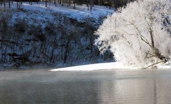 a serene winter landscape with snow - covered trees , a frozen lake , and a calm body of water at Rocky River Inn
