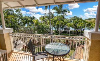 a balcony overlooking a body of water , with a table and chairs set up for outdoor dining at On the Beach Apartments