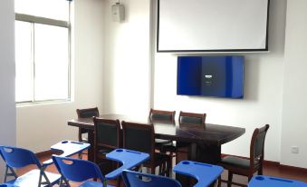 There is a classroom with blue chairs and tables in front, and a projector screen is positioned on top at Yuhang Hotel