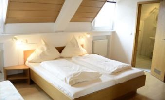 a large bed with white linens is situated in a room with slanted ceilings and wooden walls at Loewen
