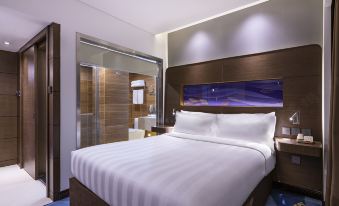 A bedroom with a large bed and balcony is located in the middle, with an open space beside it at Novotel Beijing Peace