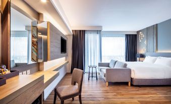 a modern hotel room with a large bed , couch , dining table , and other amenities at Hotel Amber Pattaya