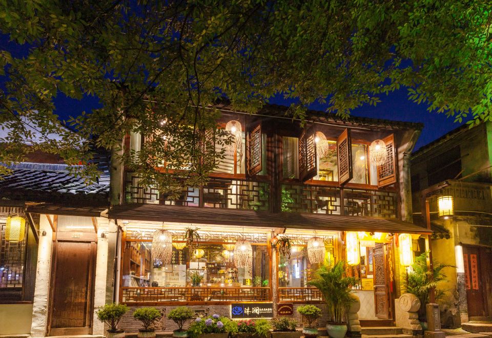 The building where a hotel is located is illuminated at night by street lamps on both sides at Zhouzhuang Latte Play Stone Mulan Hotel