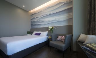 The hotel's main living area includes a bedroom with a double bed, a chair, and artwork at V Hotel Lavender