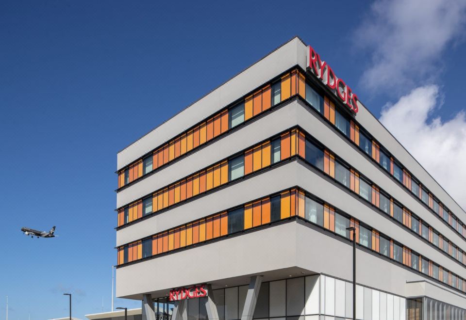 "a modern , white and orange building with the letters "" ryd "" on top , under a clear blue sky" at Rydges Wellington Airport, an EVT hotel