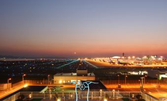 an airport at night , with a runway visible in the distance , illuminated by colorful lights at Hotel Nikko Kansai Airport