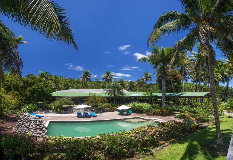 a resort with a large pool surrounded by palm trees and lounge chairs , creating a tropical atmosphere at Maravu Taveuni Lodge