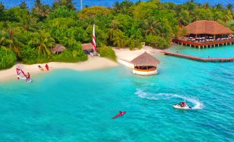 aerial view of a man riding a jet ski on a beach , surrounded by clear blue water and lush greenery at Eriyadu Island Resort