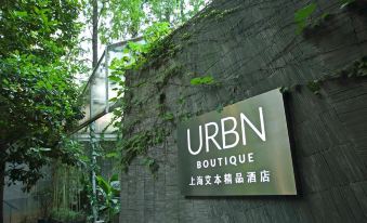 There is outdoor seating in front of a building with signage on its walls and entrance at URBN Boutique Shanghai
