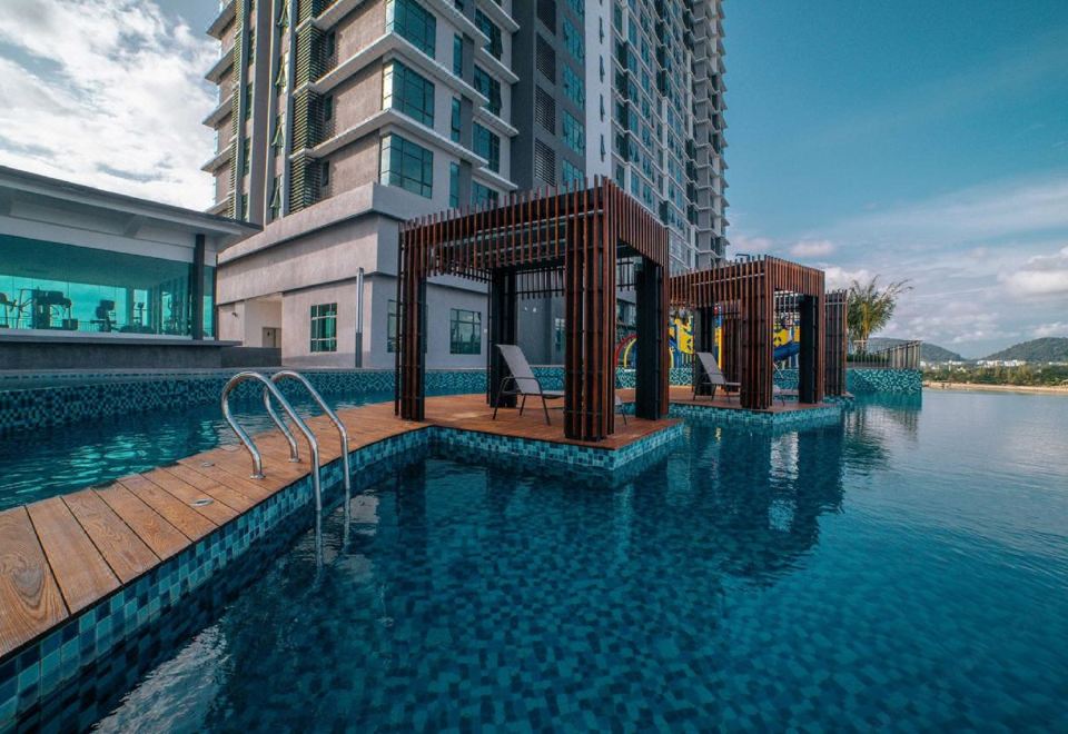 a swimming pool surrounded by a building , with people enjoying their time in the pool at Swiss-Belhotel Kuantan