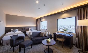 a hotel room with two beds , a couch , and a table , all situated in a modern style at Kawasaki Nikko Hotel