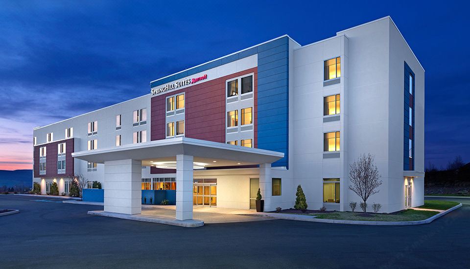 a large , white hotel building with a blue and red facade , lit up at night at SpringHill Suites Dayton Vandalia