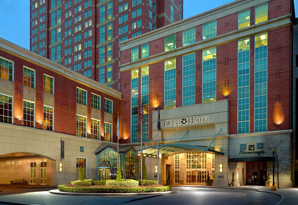 the entrance to the the hilton garden inn hotel in hong kong , with its red brick exterior and green bushes on either side at Omni Providence