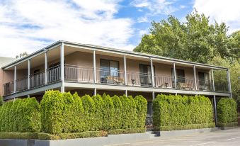a two - story building with a parking lot in front and greenery on one side , under a blue sky at Barkly Motorlodge