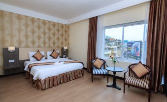 a modern hotel room with two beds , a desk , and a window offering a view of the city at Paradise Hotel