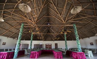 a large room with wooden beams and thatched ceiling , featuring several tables and chairs arranged for a meeting or event at AA Lodge Amboseli