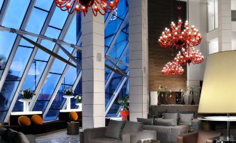 a modern hotel lobby with large windows , multiple seating areas , and red chandeliers hanging from the ceiling at Antony Palace Hotel - Venice Airport