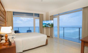 a modern bedroom with large windows offering a view of the ocean , featuring a bed and a flat screen tv at Marino Beach Colombo