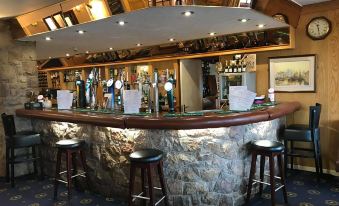 a bar with a stone counter and stools , surrounded by bottles of alcohol on shelves at The Anchorage Hotel