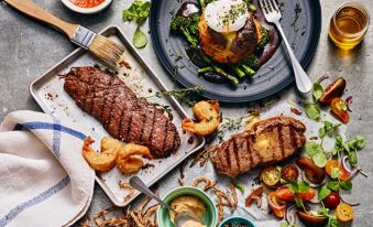 a table is set with various dishes , including a steak and onion rings , as well as a fork and knife at Leeds / Bradford Airport