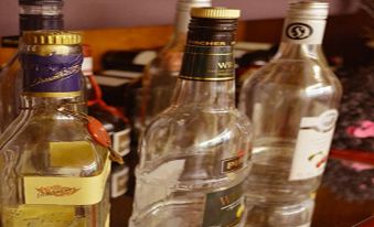 several empty bottles of various brands of alcohol , such as vodka and wine , arranged on a shelf at Hoffmann