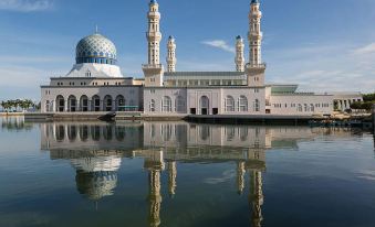 a large , ornate mosque with multiple domes and minarets is reflected in the water below at The Gem Hotel Beaufort