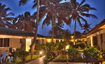 a nighttime view of a resort with palm trees , a path leading to the buildings , and lights illuminating the area at Sunset Beach Hotel