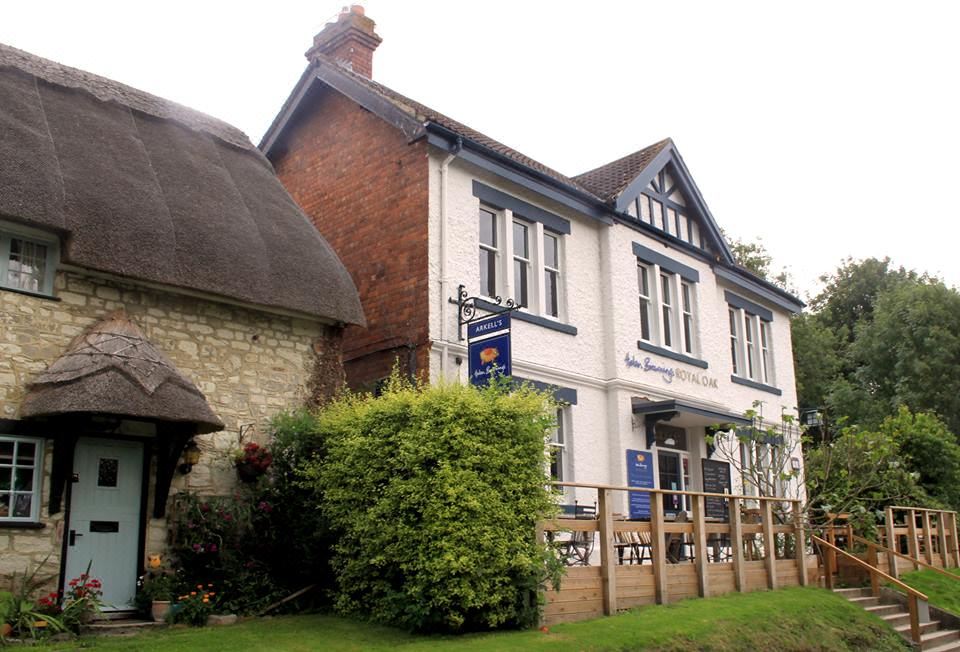 a brick building with a blue sign on the front , located in a rural area at Helen Browning's Royal Oak