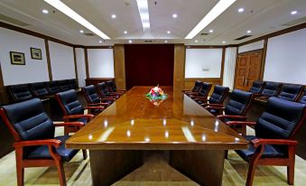 There is a large conference room with a wooden table and black chairs available for meetings or boardroom use at Byfond Hotel