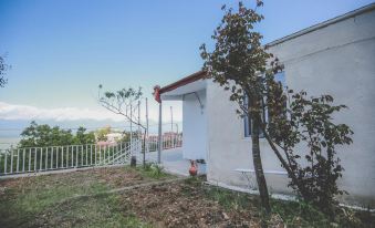 a house with a white exterior and red roof is surrounded by trees and has a view of the ocean at Veranda