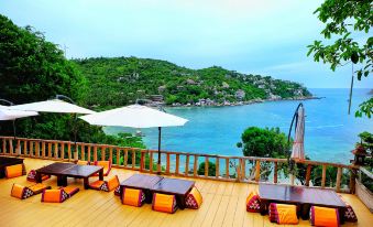 a wooden deck overlooking the ocean , with several lounge chairs and umbrellas placed on the deck for relaxation at Taatoh Seaview Resort