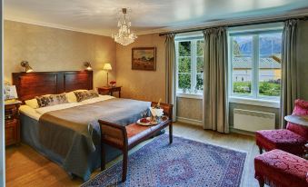 a large bedroom with a king - sized bed , hardwood floors , and a large window overlooking the outdoors at Fretheim Hotel