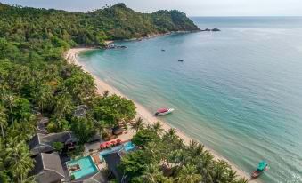 a beautiful beach with a clear blue sea and white sand , surrounded by lush green trees at Anantara Rasananda Koh Phangan Villas