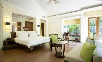 a spacious bedroom with a large bed , a couch , and a dining table in the room at Robinson Khao Lak