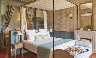 a large bed with white linens and a canopy is in a room with patterned wallpaper at Chateau de Fonscolombe