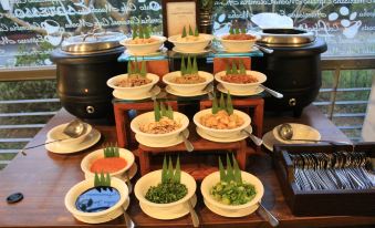 a table is filled with multiple bowls of food , each containing different types of vegetables and sauces at Forbis Hotel