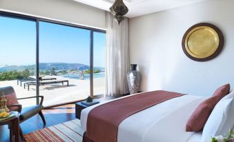 a bedroom with a large bed , white walls , and a view of the ocean through a window at Anantara Al Jabal Al Akhdar Resort