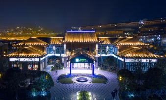 a nighttime view of the beijing international trade and exhibition center , with its distinctive blue and gold - colored structures illuminated against the dark night sky at Holiday Inn Express