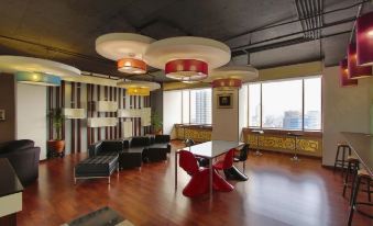 a modern office space with wooden floors , large windows , and multiple tables , one of which is red and black at Jayakarta Hotel Jakarta