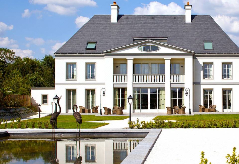 a large white house with a pool in the backyard , surrounded by trees and grass at Hôtel la Ramade