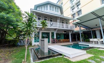 a large white house with a pool in the backyard , surrounded by green grass and trees at Viva Hotel Songkhla
