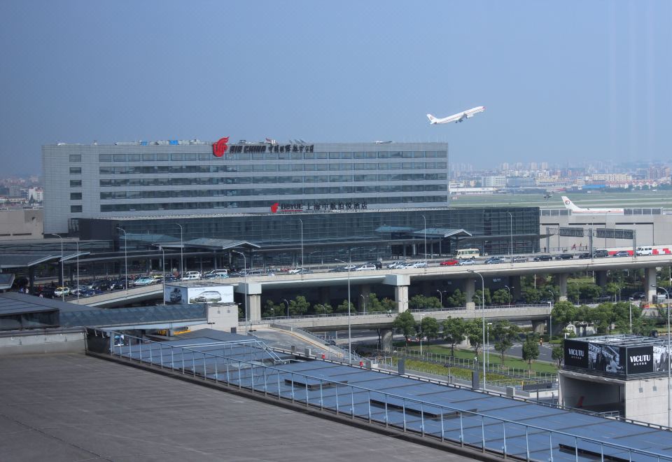 There is a large building with an airport in the background and a plane on top at one end at Boyue Hotel Shanghai Air China Hongqiao Airport