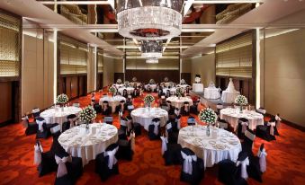The ballroom is elegantly decorated with tables set for an event and chandeliers hanging in the center at Pan Pacific Hanoi