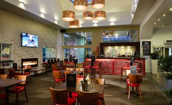 a large dining room with multiple tables and chairs , as well as a bar area at Garden Hotel