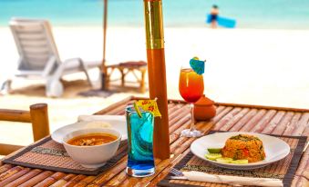 a dining table set up on the beach , with a variety of food and drinks placed on it at Mali Resort Pattaya Beach Koh Lipe